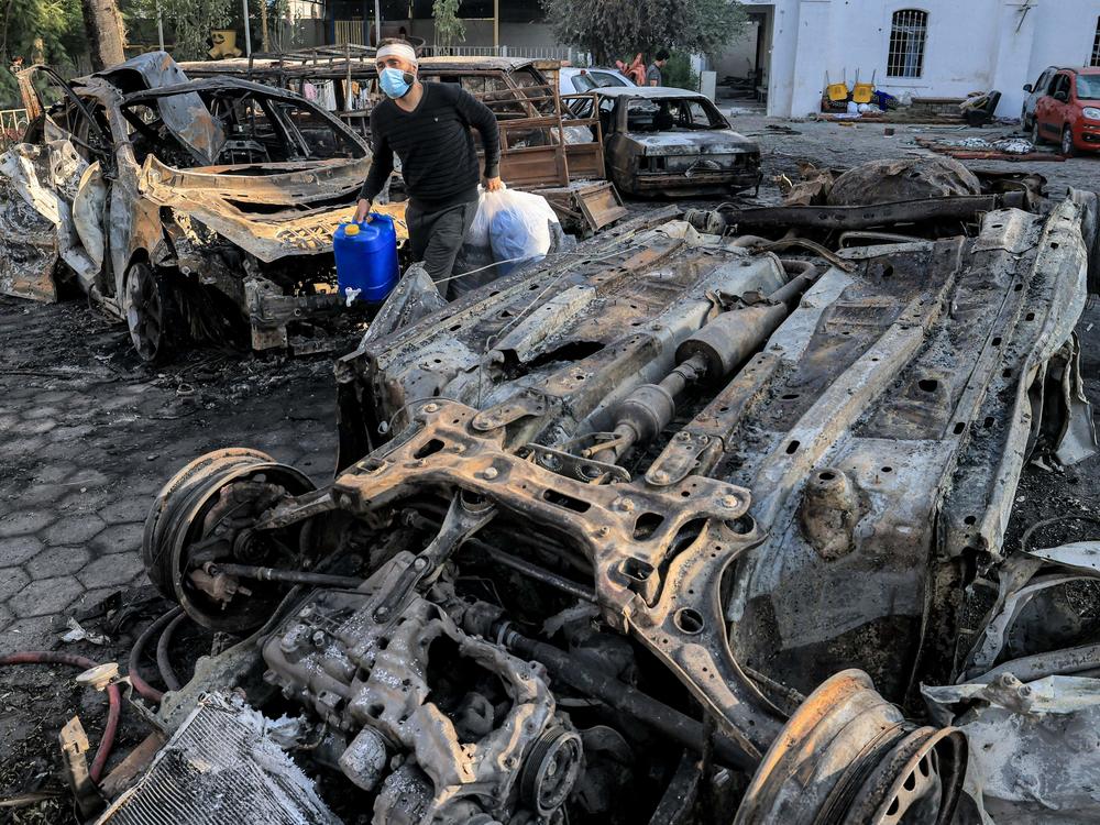A man walks past destroyed vehicles at the site of the Ahli Arab hospital in Gaza where an explosion killed hundreds of people, sparking global condemnation and angry protests around the Muslim world.