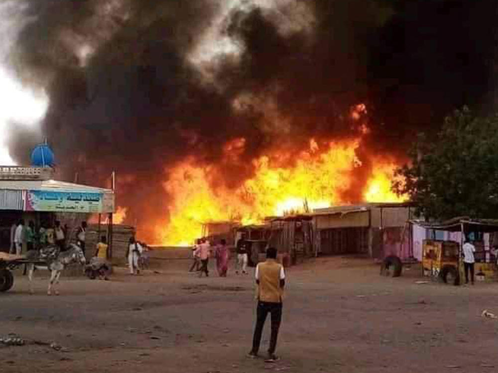 A man stands by as a fire rages in a livestock market area in al-Fasher, the capital of Sudan's North Darfur state, on Sept. 1, in the aftermath of bombardment by the paramilitary Rapid Support Forces (RSF).