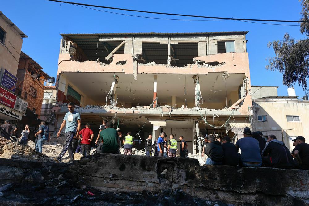 People gather in front of a damaged building following a raid by Israeli troops on the Palestinian Nur Shams camp in the occupied West Bank.