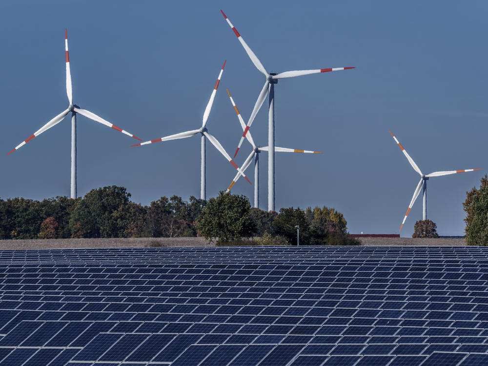 Wind turbines turn behind a solar farm in Rapshagen, Germany in 2021. The International Energy Agency projects demand for fossil fuels will peak before 2030 as renewable energy continues to grow.