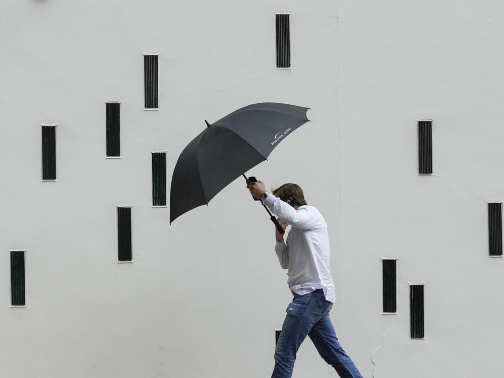 A man walks in the rain along a street in Austin, Texas, Nov. 11, 2022.