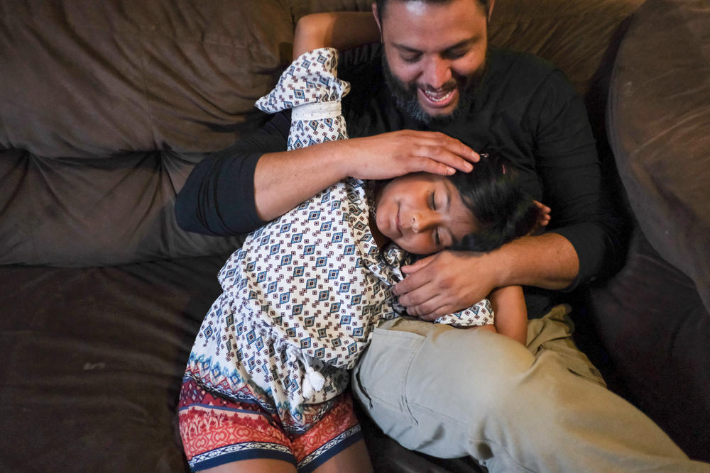 Jose Grajeda and his daughter, Victoria, cuddle before bedtime in Alpine, Tex. When Grajeda was a kid, he remembers how his parents employed a soothing caress to send him to sleep. Now he uses it with his kids. 