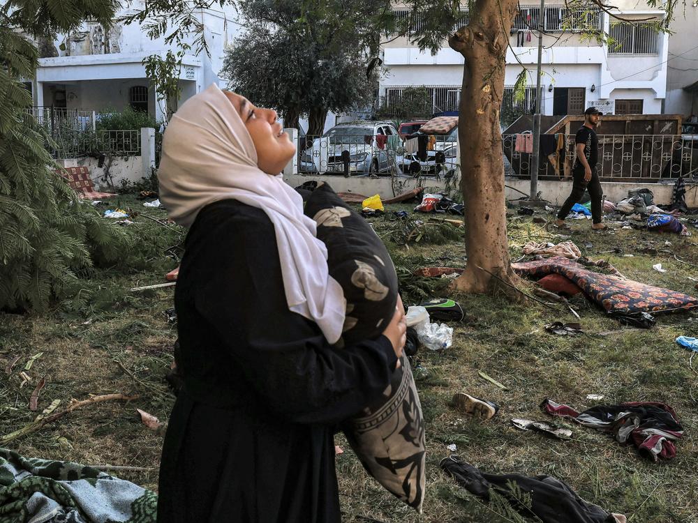 A woman holds a pillow near the Al Ahli Arab Hospital in Gaza City, the site of a blast that killed hundreds on October 17. In the aftermath, Hamas and Israel traded blame.