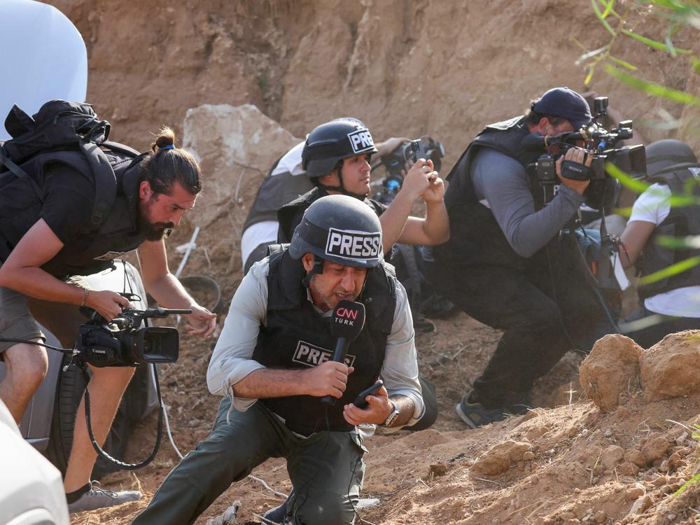 Reporters take cover upon hearing sirens warning of an incoming rocket attack from Gaza, in the southern Israeli city of Sderot, on Monday.