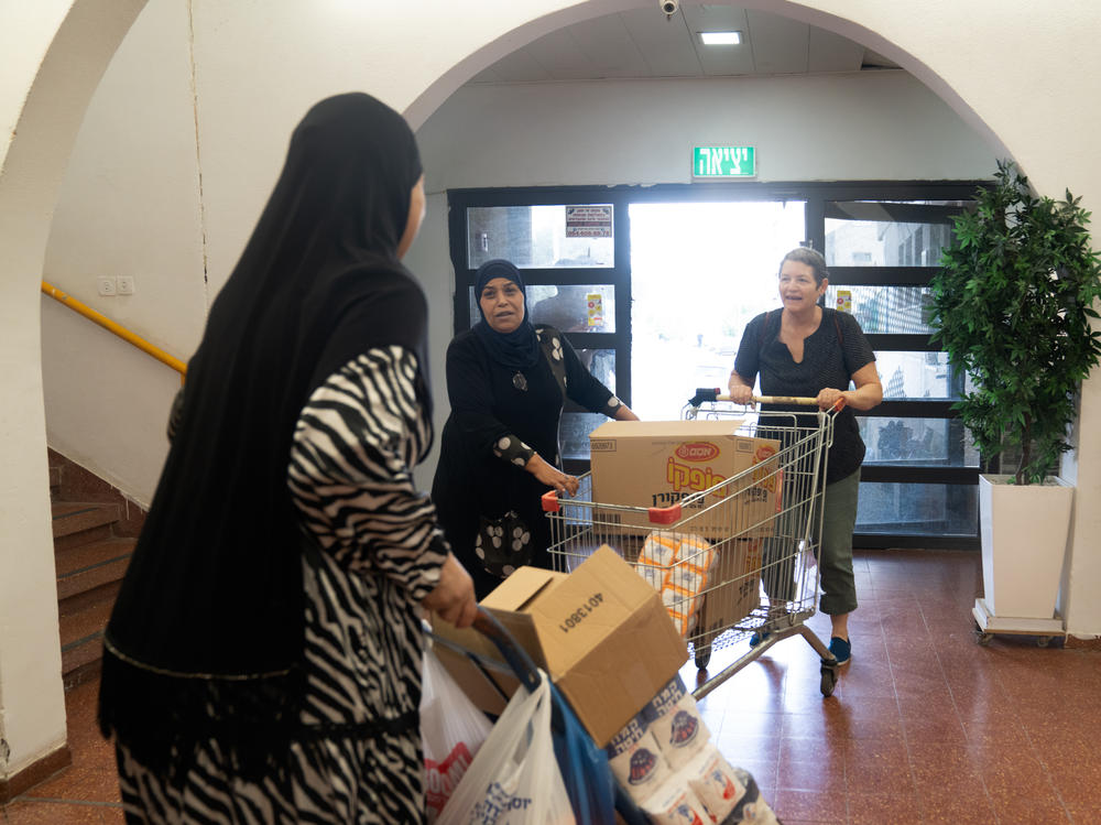 Smadar Tzimmerman (right) helps push a cart with donations into the community center in Lod, Israel.