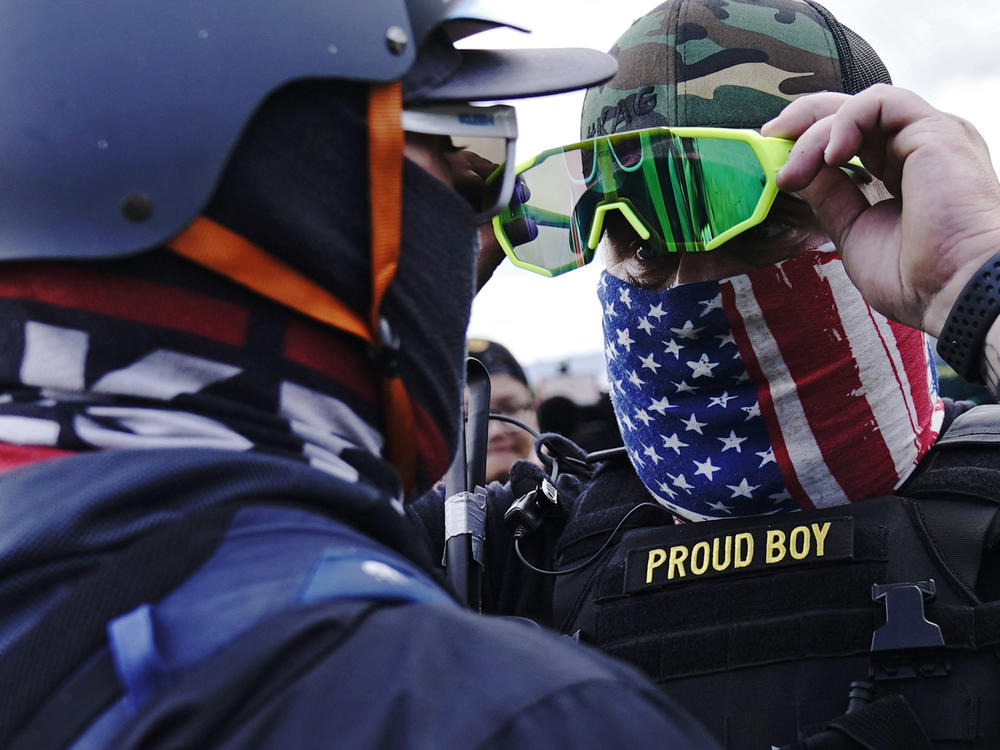 In this file photo, a member of the Proud Boys, right, stands in front of a counter protester as members of the Proud Boys and other right-wing demonstrators rally on Sept. 26, 2020.