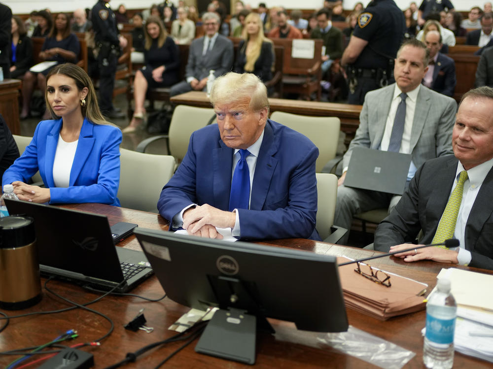 Former President Donald Trump, center, flanked by his defense attorneys, Alina Habba, left, and Chris Kise, right.