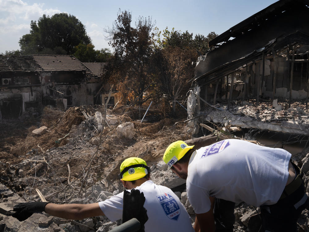 Men working with a search and recovery team from the organization ZAKA look for human remains in Kibbutz Be'eri.