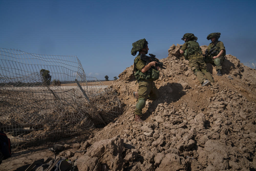 Israeli soldiers look over the edge of Kibbutz Be'eri.