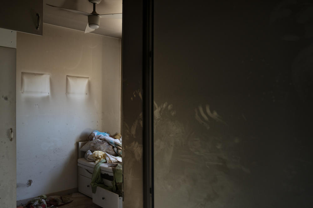 Hand prints are seen in soot and blood stains cover the sheets of a bed in a home in Kibbutz Be'eri.
