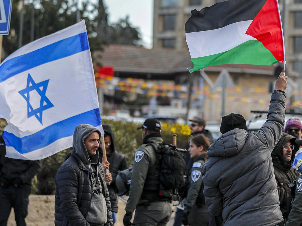 An Israeli settler stands with an Israeli flag before a man holding up a Palestinian flag during a demonstration in the East Jerusalem neighborhood of Sheikh Jarrah in February 2022.