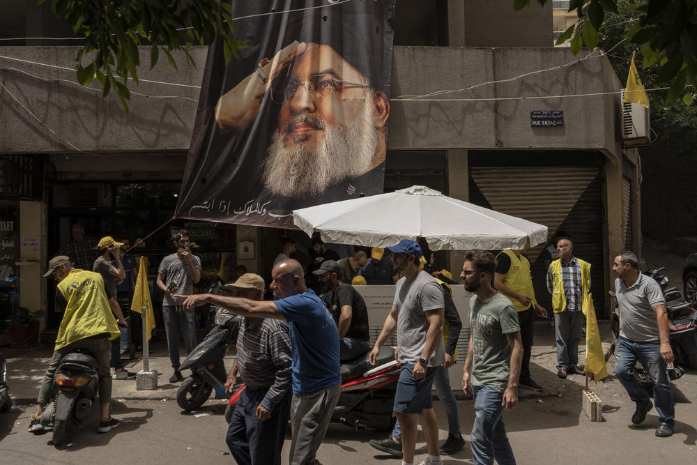 People pass a poster featuring Hassan Nasrallah, secretary general of the Hezbollah party, during parliamentary elections in Beirut, Lebanon, on May 15, 2022.