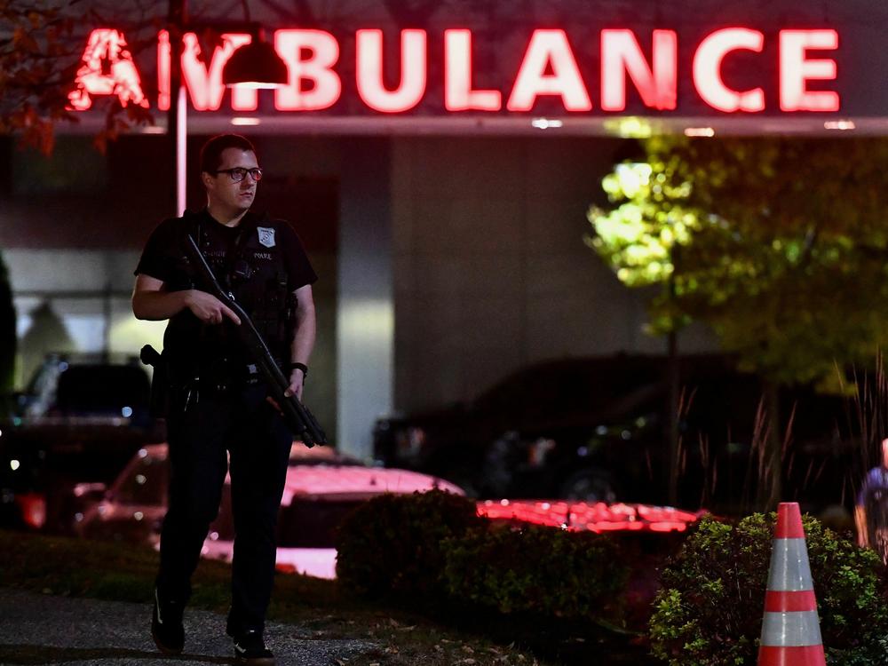 An armed police officer guards the ambulance entrance to the Central Maine Medical Center in Lewiston, Maine, early on Oct. 26, 2023. A massive manhunt was under way for 40-year-old Robert Card, who officials identified as a person of interest.