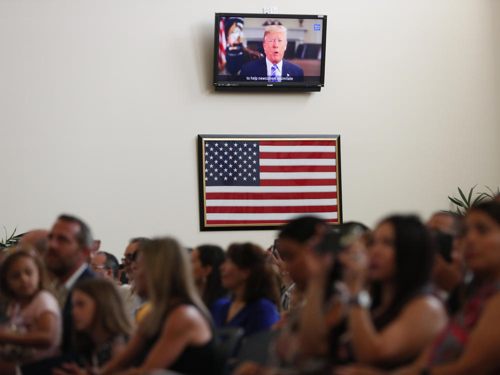 A recorded video message by then-President Donald Trump plays at a 2019 naturalization ceremony for new U.S. citizens at the U.S. Citizenship and Immigration Services field office in Miami.