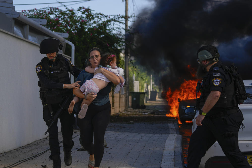 Israeli police officers evacuate a woman and a child from a site hit by a rocket fired from the Gaza Strip, in Ashkelon, Israel, on Oct. 7.