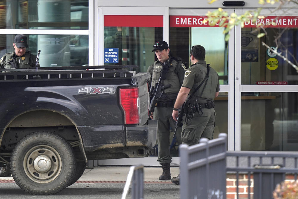 Law enforcement officers carry rifles near an emergency department entrance at Central Maine Medical Center in Lewiston, Maine, on Thursday. This week's mass shooting in Lewiston left 18 people dead.