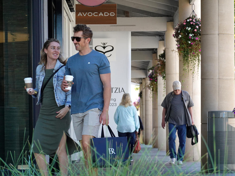 A shopper carries a shopping bag while walking through an outdoor shopping center in Corte Madera, Calif., on Oct. 17. Strong consumer spending is helping to power the economy — but it may not last.