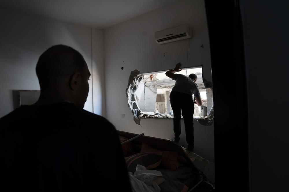 Noor Damaj (left) looks on as a fellow Jenin resident surveys the mosque destruction through a bedroom window at his home.