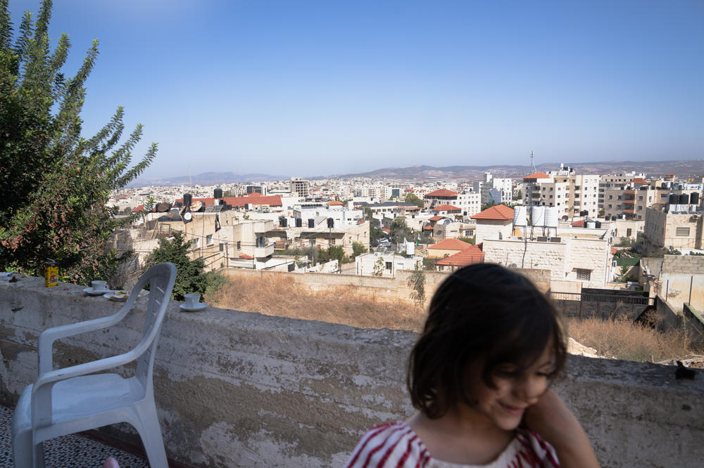 Maie Zakarneh, 3, passes in front of a view of Jenin refugee camp. More than 10,000 people live in the camp.