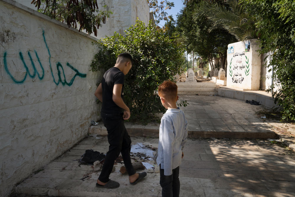 Boys look at a ripped T-shirt and blood on the ground at the site of an Israeli drone strike that killed two teenagers and one 20-year-old in Jenin refugee camp.