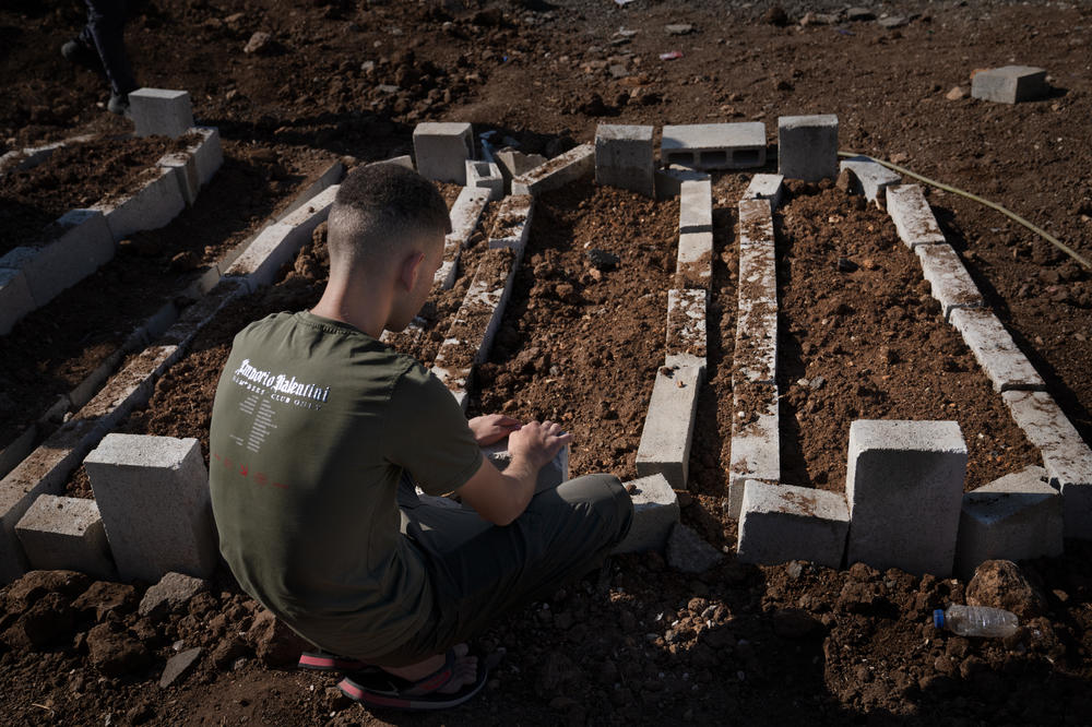 A young man sits by the fresh graves of the two teenagers and one 20-year-old killed in the recent Israeli drone strike in Jenin.