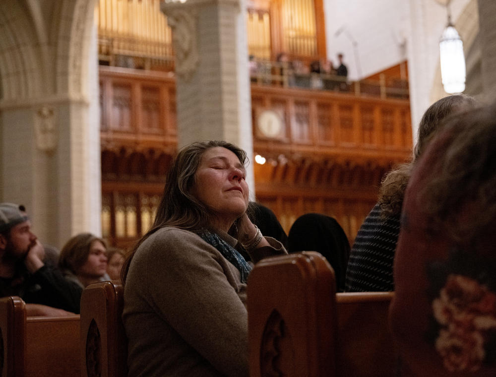 At the OneLewiston Community Vigil, an attendee closes their eyes as the Bates College Crossbones perform <em>Run to You</em> by the Pentatonics in the Basilica of Saints Peter and Paul in Lewiston, Maine.