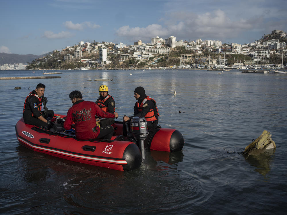 Firefighters and divers search for bodies near sunken boats at a yacht club in Acapulco, Mexico, on Saturday, Oct. 28, 2023, following Hurricane Otis.