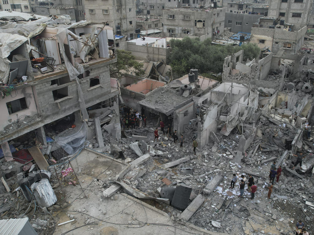Palestinians walk about buildings destroyed in the Israeli bombardment in the Nusseirat refugee camp in the Gaza Strip on Sunday.