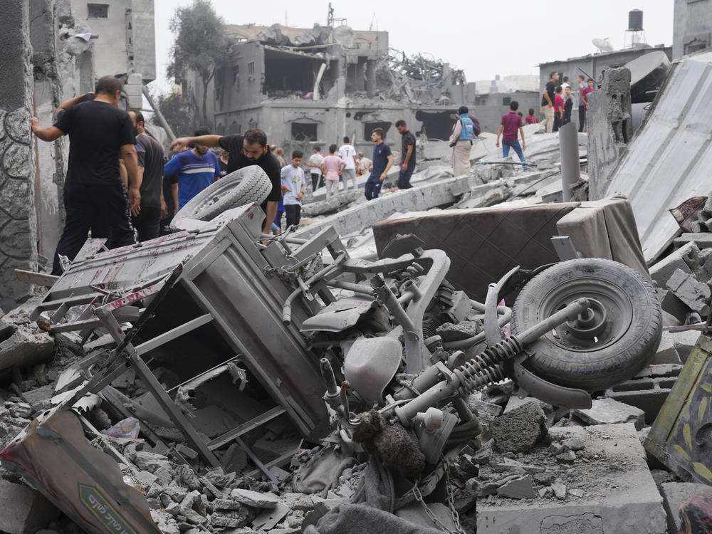 Palestinians walk about buildings destroyed in the Israeli bombardment in the Nusseirat refugee camp in the Gaza Strip on Sunday.