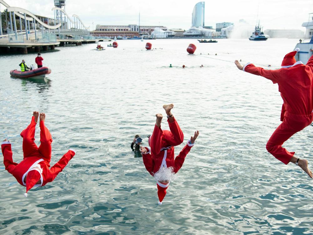 Participants sporting Santa Claus costumes jump into the water during the 111th edition of the Copa Nadal swimming race in Barcelona's Port Vell on December 25, 2020.