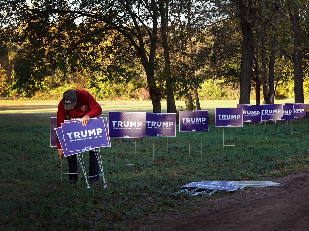 A worker sets up signs at the Dallas County Fairgrounds for a rally with Republican presidential candidate and former President Donald Trump on Oct. 16 in Adel, Iowa.