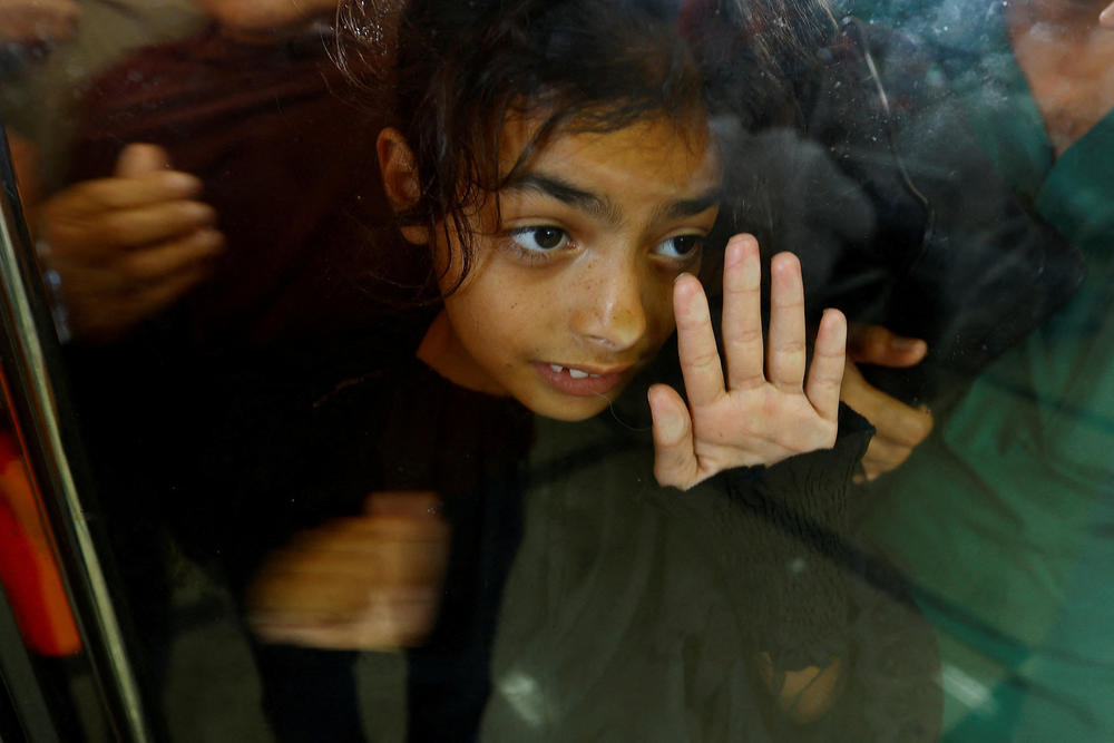A child looks through glass, as Palestinians with dual citizenship wait at the Rafah border crossing with Egypt on November 1, 2023.