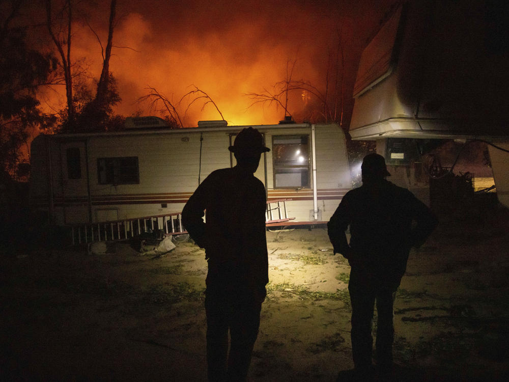 A firefighter and resident converse on how to protect his possessions as a wildfire called the Highland Fire burns in Aguanga, Calif., on Monday.