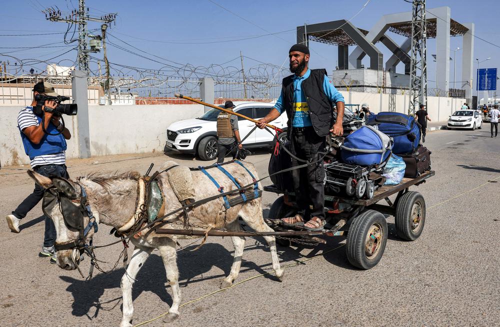 A journalist films a man driving a donkey-drawn cart carrying luggage outside the Rafah border crossing with Egypt in the southern Gaza Strip on Wednesday.