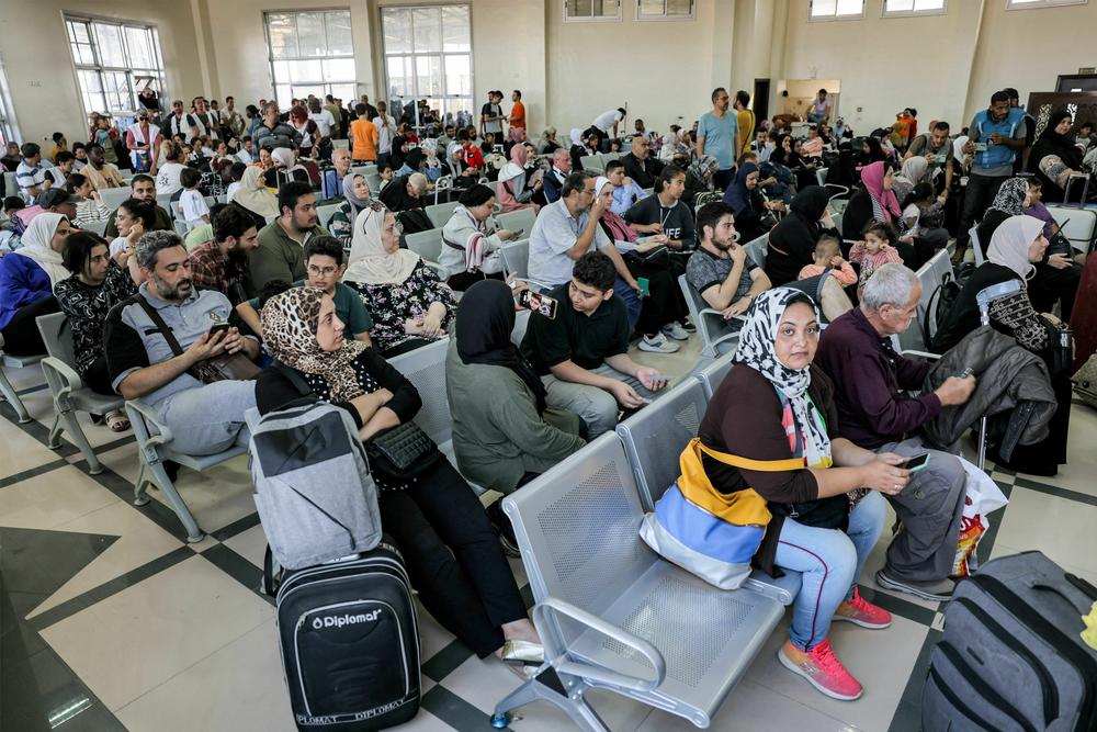 People sit in the waiting area at the Rafah border crossing in the southern Gaza Strip before crossing into Egypt on Wednesday.