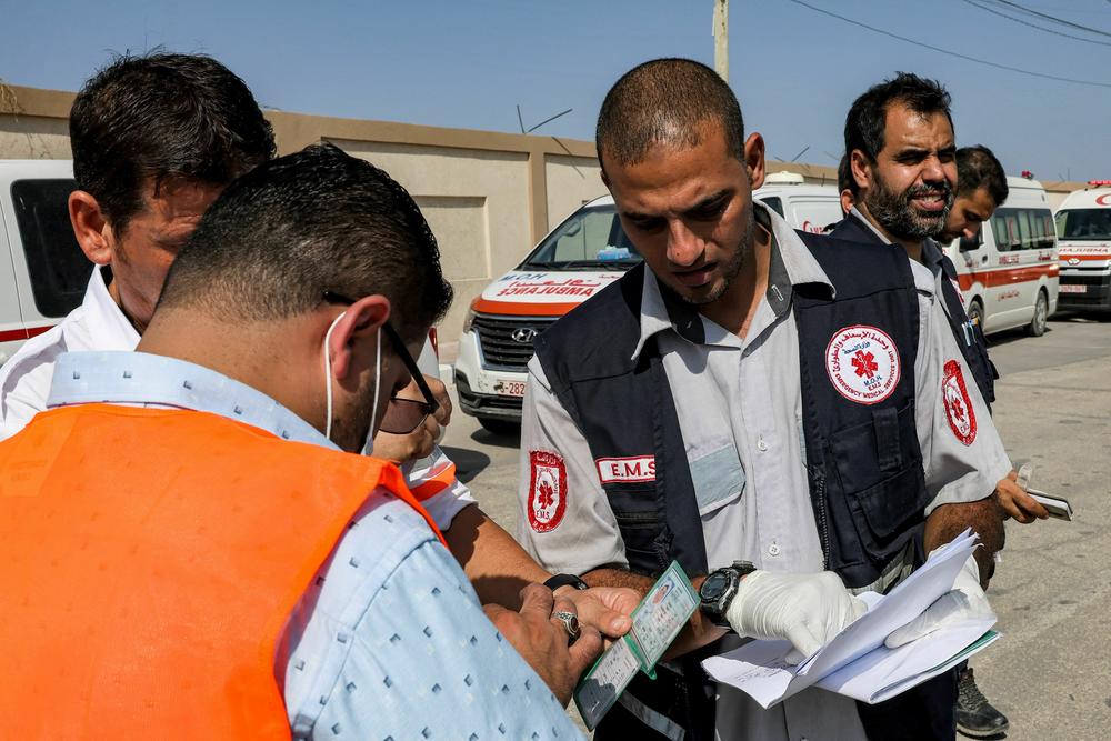 Palestinian health ministry paramedics check the travel documents of a person waiting to cross to Egypt at the Rafah border crossing.