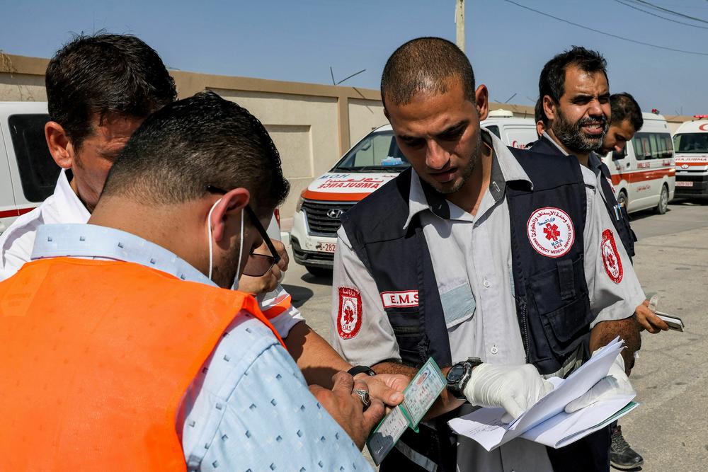 Palestinian health ministry paramedics check the travel documents of a person waiting to cross to Egypt at the Rafah border crossing in the southern Gaza Strip on Wednesday.
