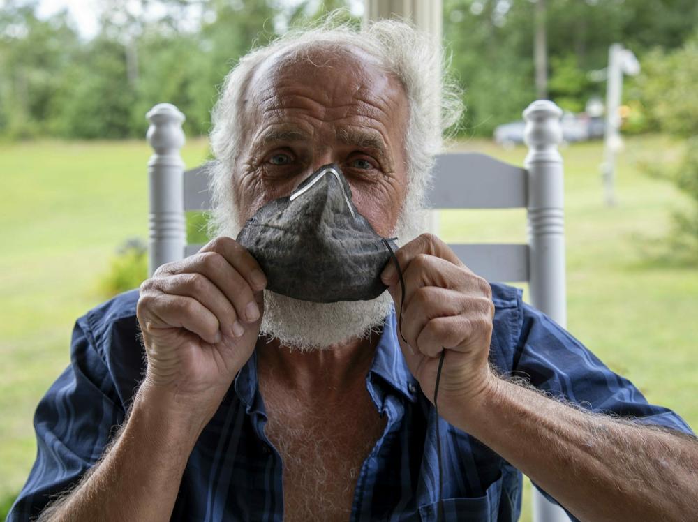 Danny Johnson, a retired coal miner with complicated black lung, holds a protective mask that used to be white, but turned black and crusted with dust during one working shift in a mine.