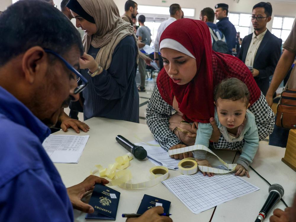Civilians leaving Gaza display their documents as dual national Palestinians and foreigners prepare to cross the Rafah border point with Egypt, in the southern Gaza Strip, on  Thursday.