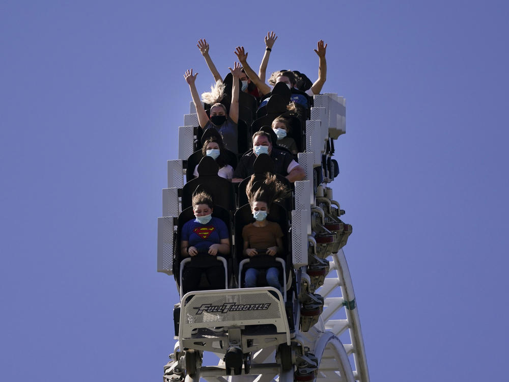 Visitors wearing masks ride on a roller coaster at Six Flags Magic Mountain on its first day of reopening to members and pass holders in Valencia, Calif., on April 1, 2021.