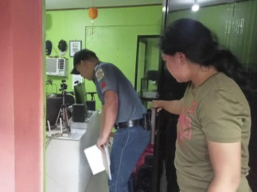 A policeman checks on the area where a radio anchor was fatally shot by a man inside his home-based station on Sunday, Nov. 5, 2023, in this handout photo provided by the Calamba Municipal Police Station. The brazen attack was witnessed by people watching the program live on Facebook.