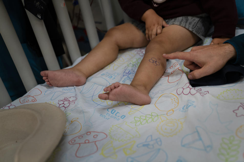 Tal Romano sits with his 4-year-old son, Hadar, who is receiving dialysis in the underground hospital in Haifa. A nurse drew a flower on Hadar's leg to make him laugh.
