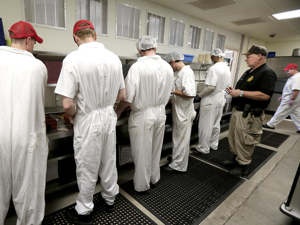 A corrections officer watches as prisoners work in the kitchen at the Ellsworth Correctional Facility in Ellsworth, Kan., in December 2015.