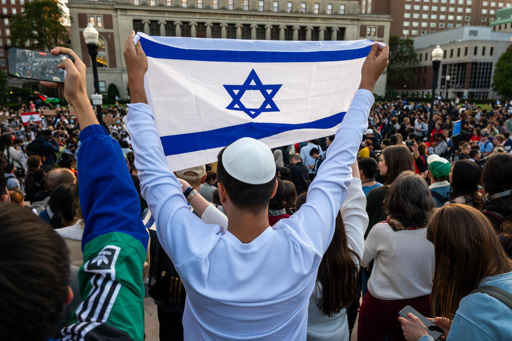 A man holds up an Israeli flag as Columbia University students participate in a rally in support of Palestine at the university on Oct. 12.