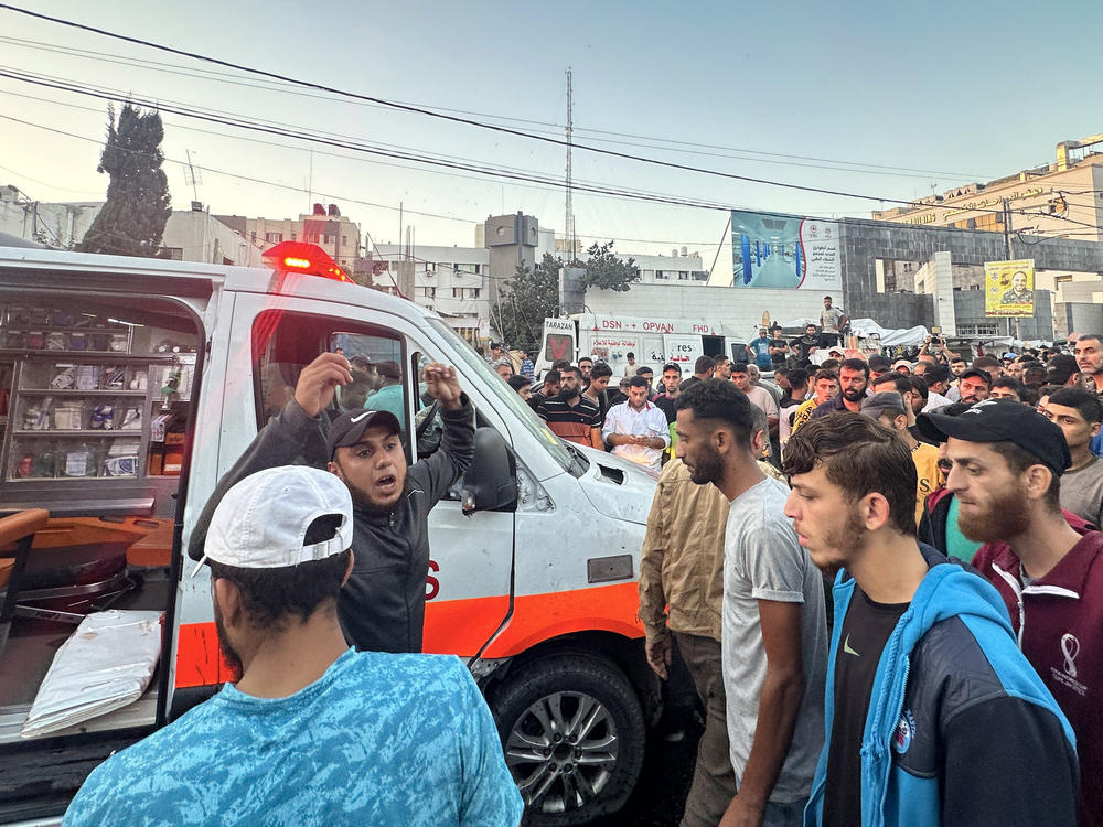 People gather around an ambulance damaged in a reported Israeli strike in front of Al-Shifa hospital in Gaza City on Nov. 3, 2023, as battles between Israel and Hamas.