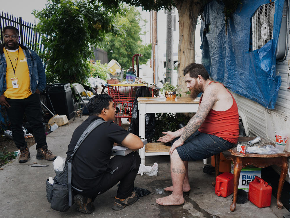 Anthony Velbis, a nurse with the homeless service agency HOPICS, checks up on Anthony Boladeres outside the RV where he's living in South Los Angeles. 