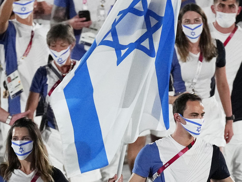 Hanna Minenko and Yakov Toumarkin, of Israel, carry their country's flag during the opening ceremony in the Olympic Stadium at the 2020 Summer Olympics in Tokyo.