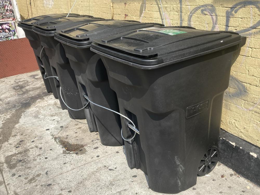 A line of wheeled waste containers sits outside a business in Manhattan, New York City, in September 2023.