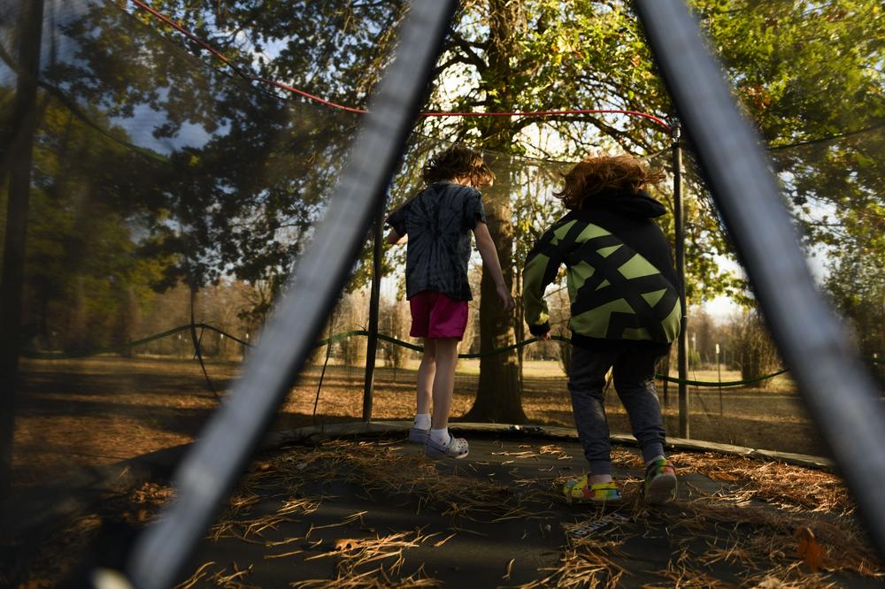 The Queens' two young children jump on a trampoline in the front yard of their home.