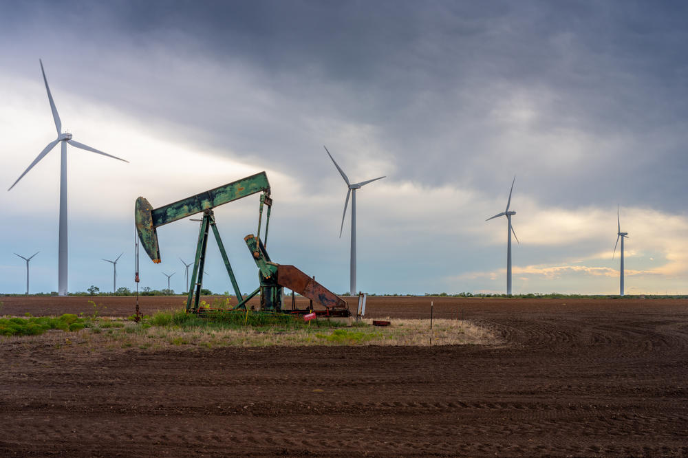 An oil pump jack stands near a field of wind turbines in Texas. Almost every piece of plastic is made from chemicals derived from fossil fuels.